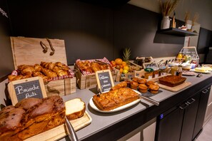 Mostrador de panadería con diversos productos horneados y un cartel de pizarra.