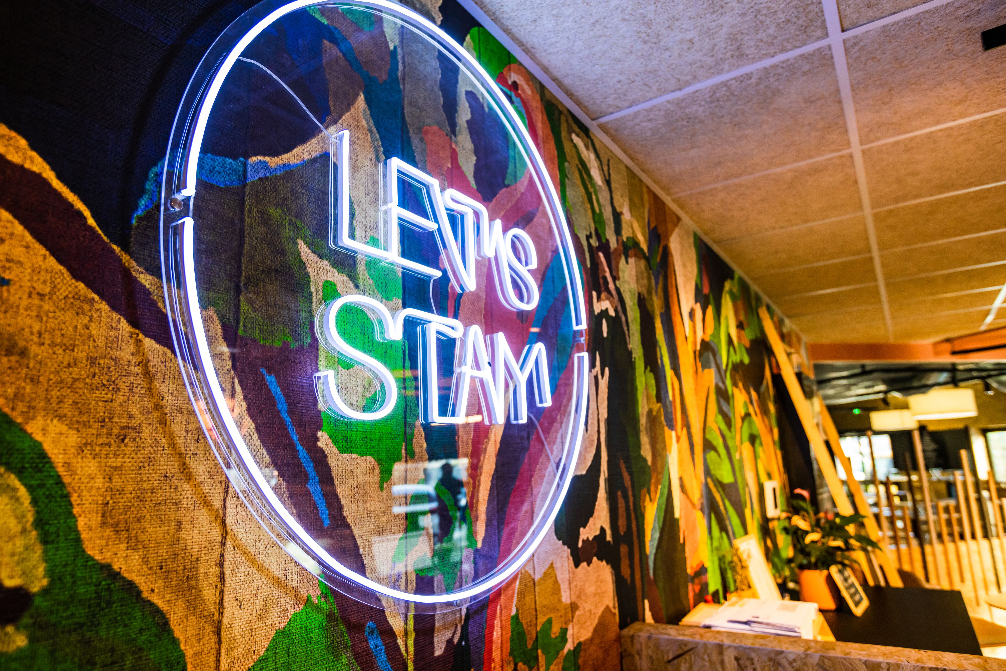 A neon sign with the text "LEVI'S STAMY" on a textured wall.