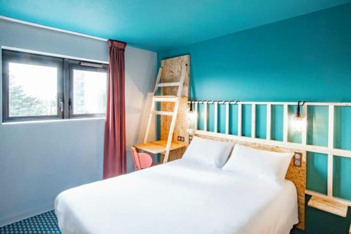Un dormitorio con cama, ventana, escalera y vistas al exterior.