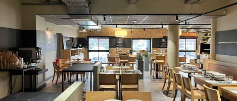Un interior de restaurante moderno con varias mesas, sillas y una zona de bar.