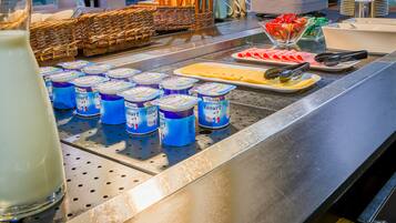 Un espace buffet proposant divers aliments et boissons, notamment des yaourts, du fromage et un verre de lait.