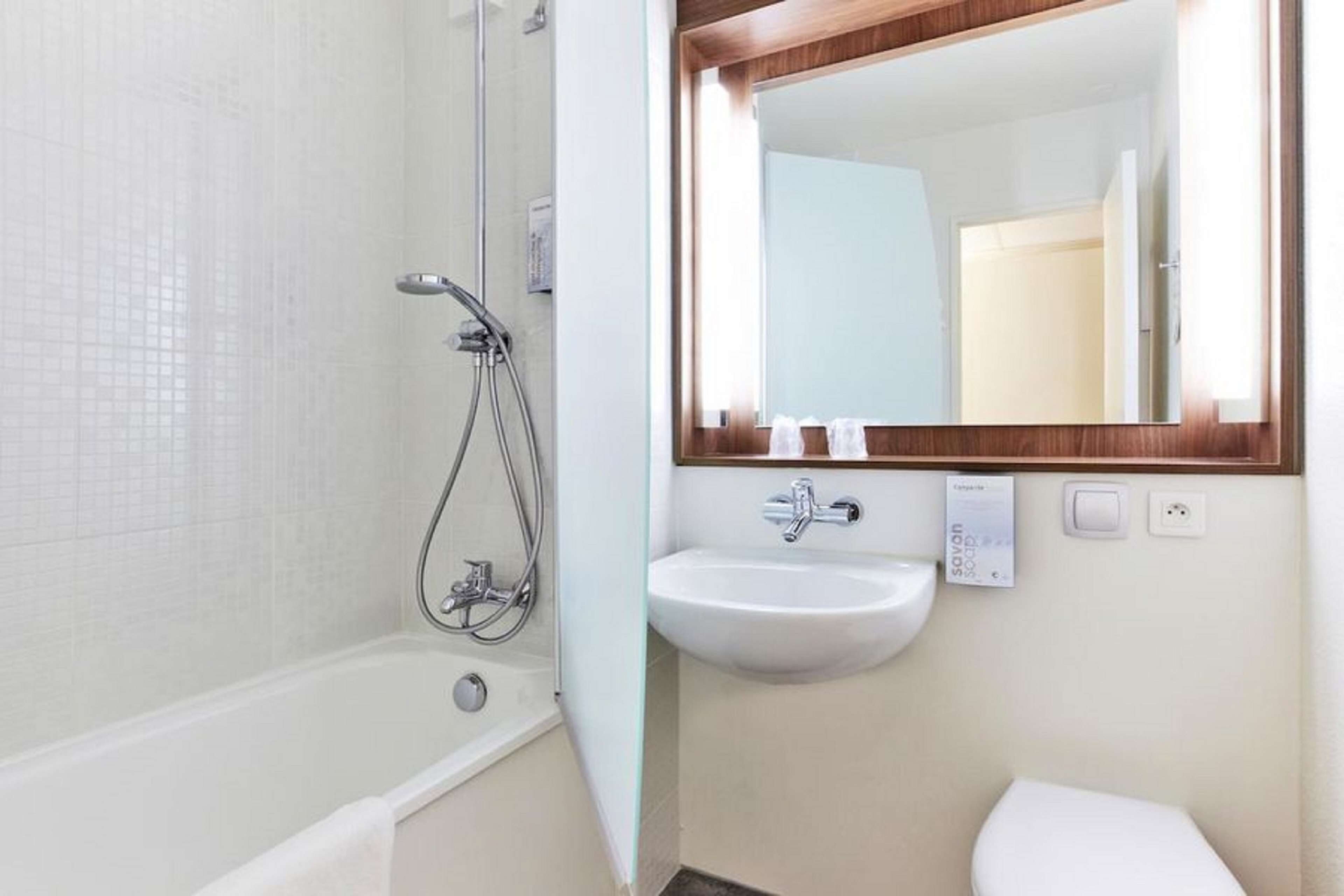 A bathroom with a bathtub, a sink, and a mirror.