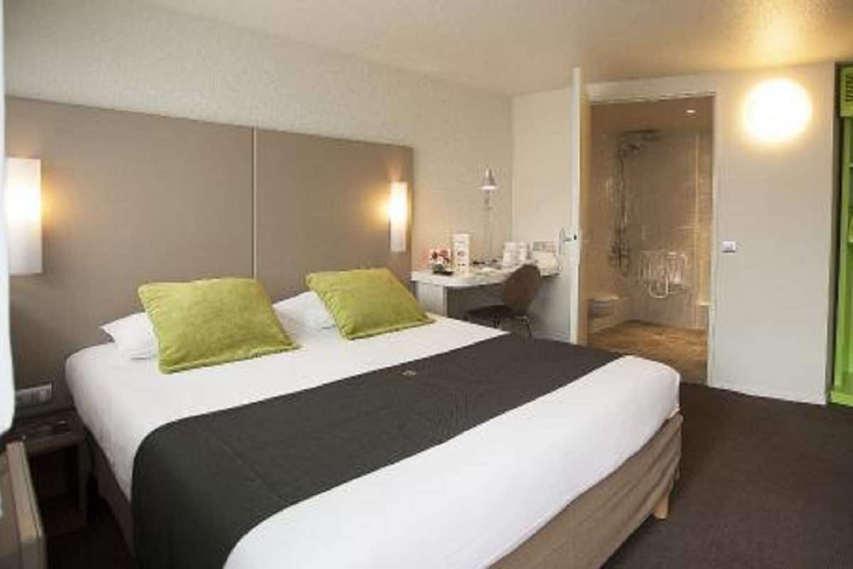 Une chambre d’hôtel avec un grand lit, un bureau et un espace douche.