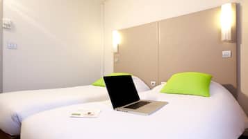 Una habitación de hotel con dos camas, un ordenador portátil sobre la cama de la izquierda y un folleto en la cama.