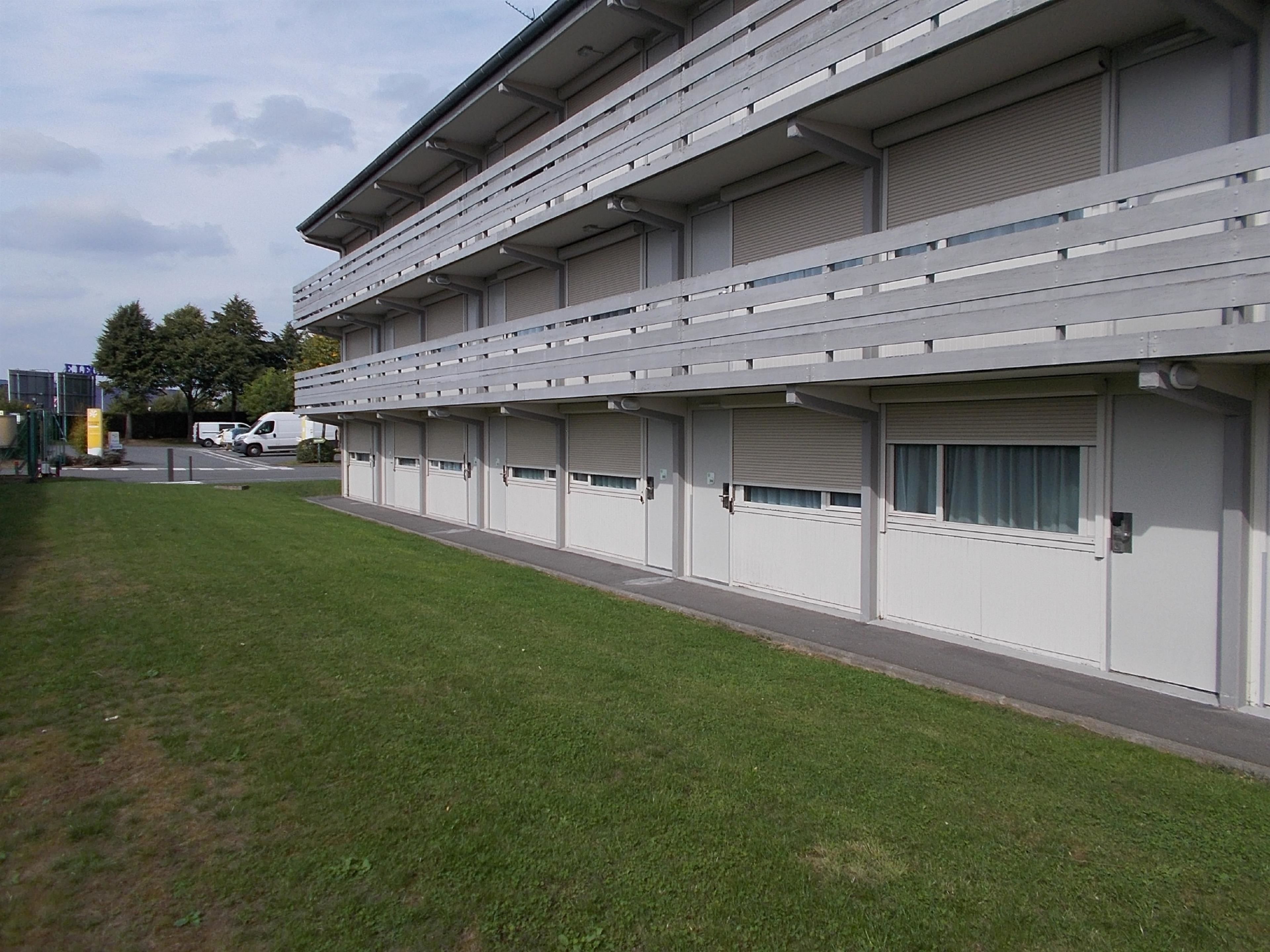 Un bâtiment moderne doté d’un toit plat, de nombreuses fenêtres et d’un espace extérieur abrité.