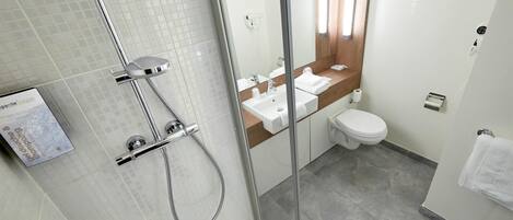 Un baño moderno con ducha de vidrio, lavamanos y retrete.