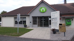 Un hôtel avec un logo vert, une enseigne et une poubelle verte.