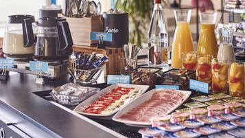 Een ontbijtbuffet met koffiezetapparaten, diverse gerechten en een assortiment aan sappen.