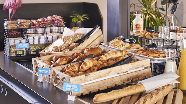 A breakfast buffet with various pastries and bread, including croissants and baguettes, in wooden crates. - Kyriad Direct Le Havre Est - Gonfreville (Gonfreville-l'Orcher)
