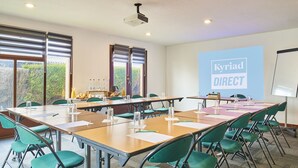 A conference room with a large table, green chairs, and a projector screen displaying "Kyriad DIRECT". - Kyriad Direct Le Havre Est - Gonfreville (Gonfreville-l'Orcher)