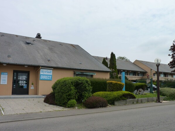 A building with a sign that reads "Kyriad DIRECT" and a welcome sign in multiple languages. - Kyriad Direct Le Havre Est - Gonfreville (Gonfreville-l'Orcher)