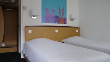 A hotel room with two beds, a wooden headboard, a wall-mounted air conditioner, and a colorful cityscape painting.