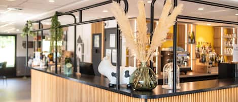 Un área de bar moderna con una barra de madera, decoración de hierba de pampa y un jarrón con forma de vaca.