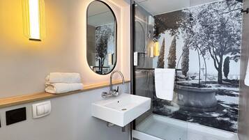 Ein modernes Badezimmer mit einem weißen Waschbecken, einem Spiegel und einer Duschkabine.