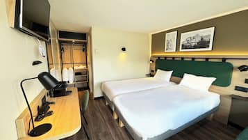 Habitación de hotel con dos camas, un escritorio con silla, televisor y armario.
