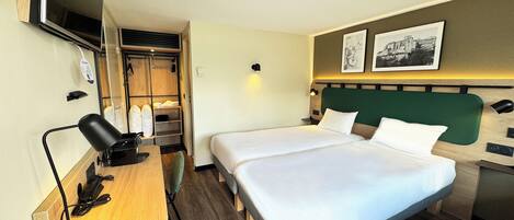 Habitación de hotel con dos camas, un escritorio con silla, televisor y armario.