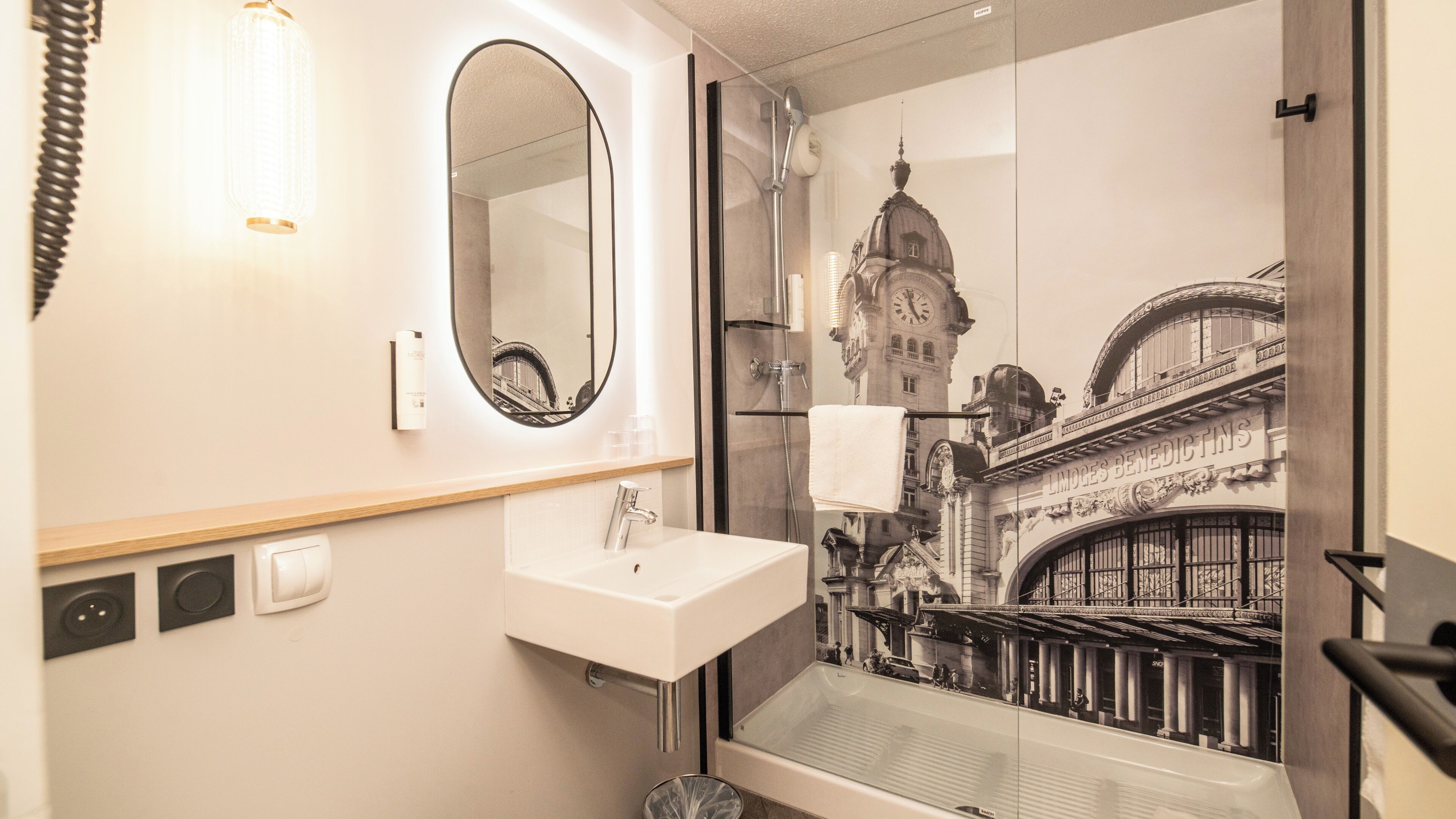 A bathroom with a large mirror, a sink, and a shower.