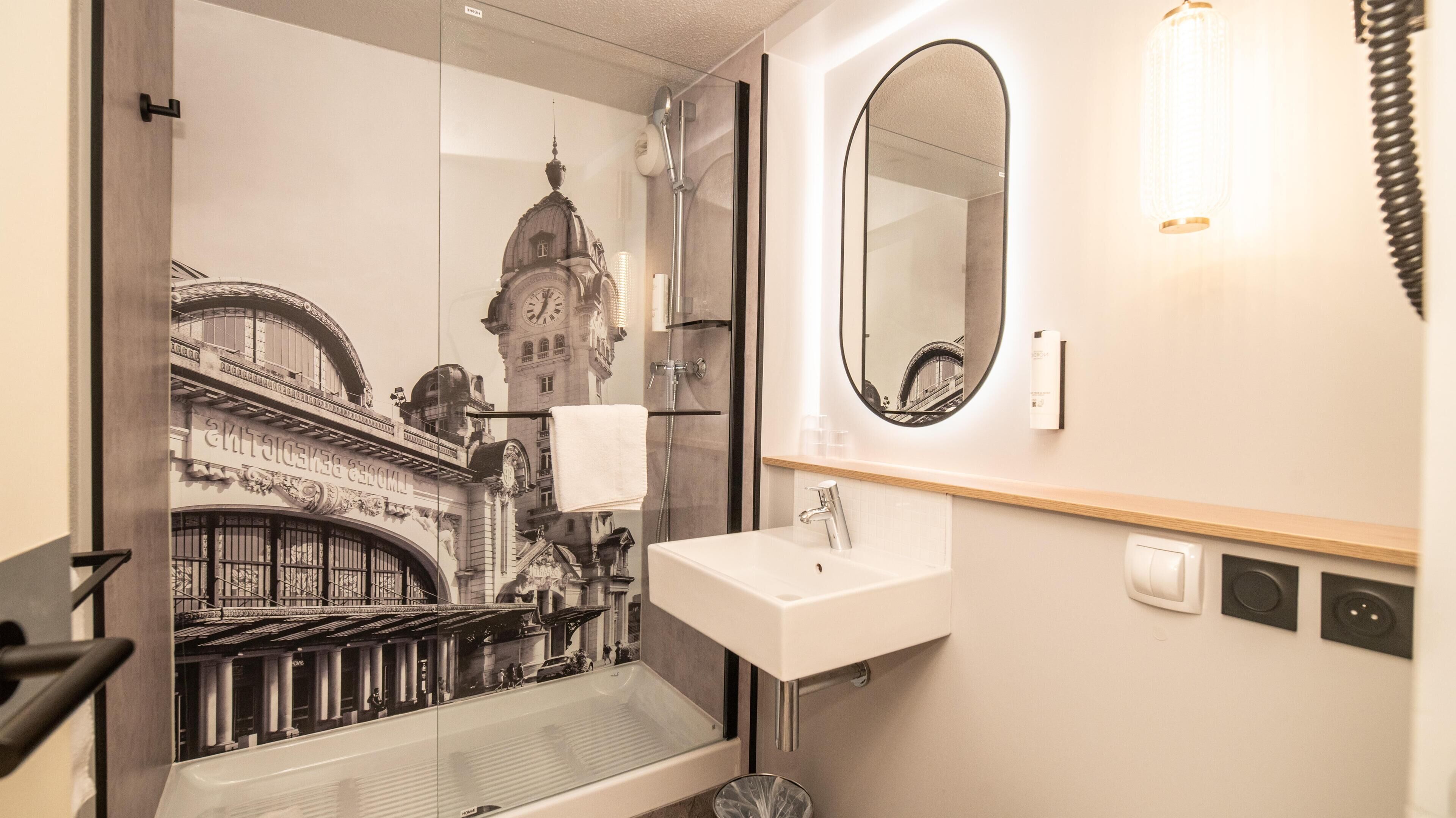 Une salle de bain moderne avec une douche à parois de verre, un grand miroir et un lavabo.