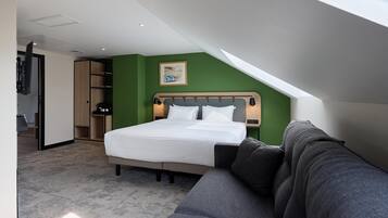 Habitación de hotel con cama, sofá, escritorio y una pared verde decorativa.