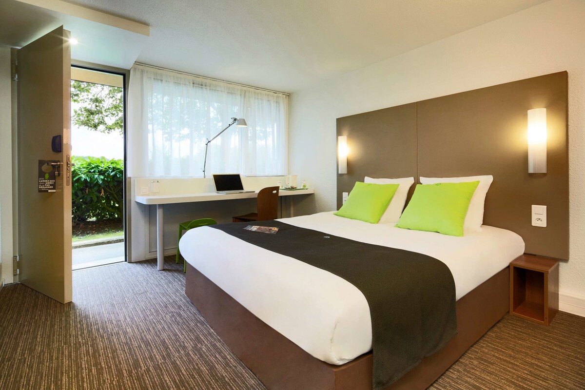 Ein Hotelzimmer mit Bett, Schreibtisch und Laptop.