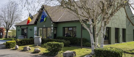 Un bâtiment à la façade verdoyante, doté d’un toit en tuiles et orné de drapeaux.