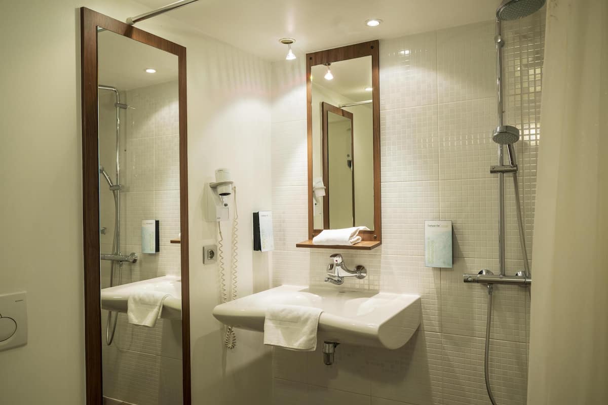 A bathroom with two sinks, a shower, a mirror, and a towel rack.
