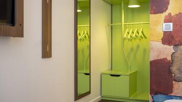Una habitación con un espejo, un armario verde y un aplique en la pared.