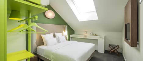 Una habitación con cama, escritorio, lámpara colgante y tragaluz.