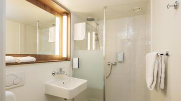 Un baño moderno con ducha de vidrio, lavamanos blanco y espejo con marco de madera.