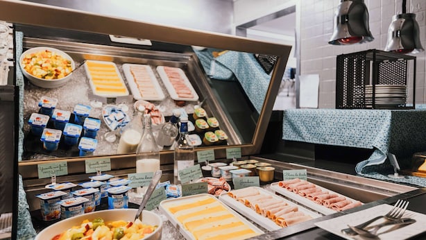 A buffet with various food items including yogurt, fruits, and meats.