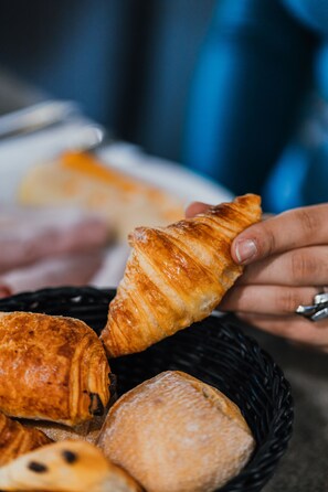 Ein Korb mit verschiedenen Backwaren, darunter Croissants und Brot.