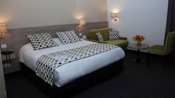 A hotel room with a large bed, two bedside tables, a chair, a small table with a vase of flowers, and two wall-mounted lamps.