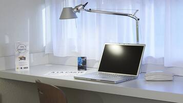 A desk with a laptop, a smartphone, a lamp, a Wi-Fi sign, and a card on a white surface.