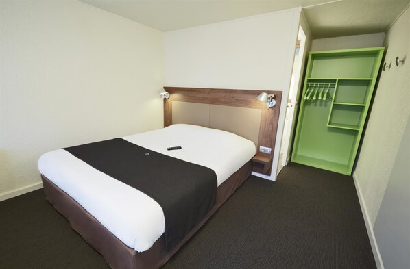 A hotel room with a bed, a green closet, and a small bedside table. - Campanile Lille Sud-CHR (Lille)