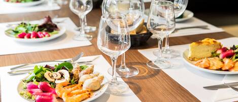 A dining table with plates of food, wine glasses, and cutlery.