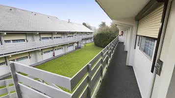 Un pasillo con vista a un edificio de múltiples ventanas y un área de césped verde.
