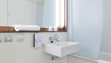 Un baño con un lavamanos blanco, un espejo y una toalla en la pared.