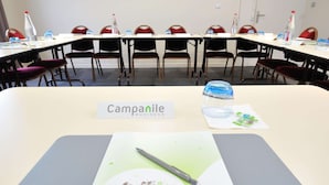 Una sala de conferencias con mesas, sillas y un letrero que dice "Campanile Business".