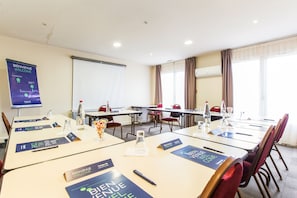 Ett konferensrum med bord, stolar, namnskyltar och en välkomstbanner.