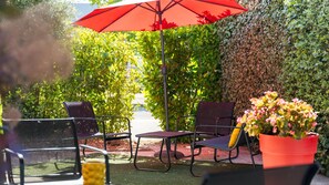 An outdoor seating area with chairs and a table, an umbrella, and a potted plant. - Campanile NATURE - Lyon Est Aéroport Saint Exupéry (Saint-Laurent-de-Mure)