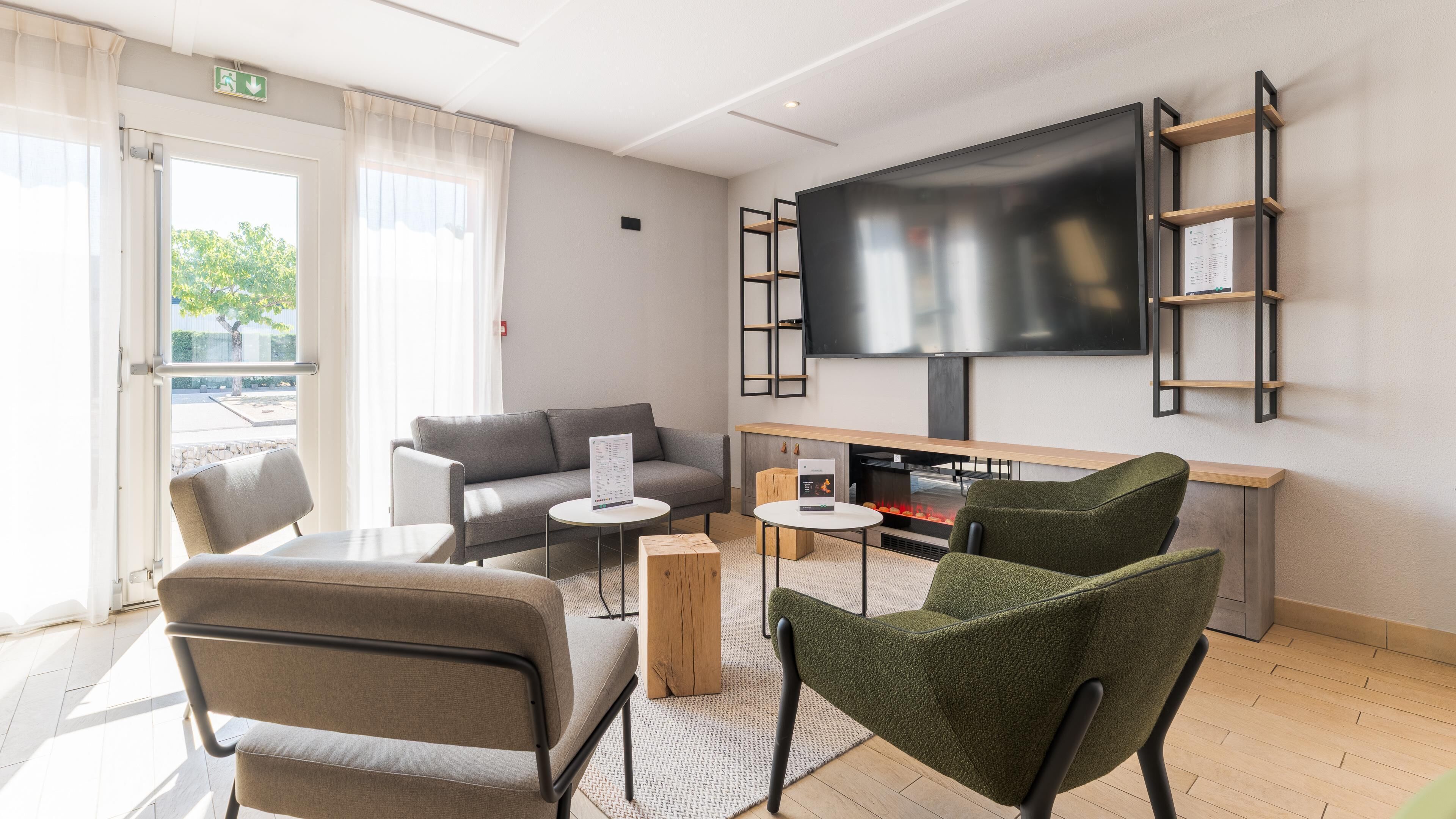 Un salon moderne doté d’un téléviseur à écran plat, d’une cheminée et d’un espace détente comprenant un canapé et des fauteuils.