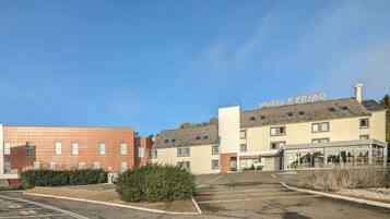 A hotel named "HOTEL KYRIAD" with a parking lot and a building with a flat roof.