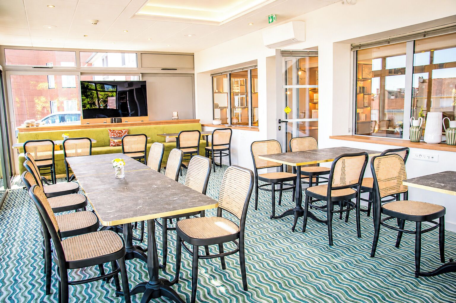 A dining area with multiple tables and chairs, a television, and a view of the outside.