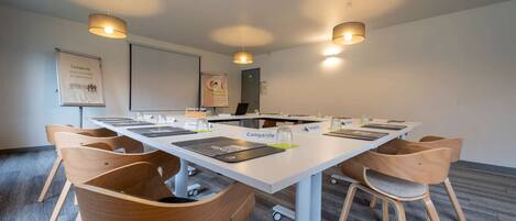 A conference room with a long table, wooden chairs, and overhead lighting.