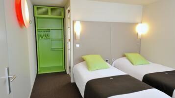 A hotel room with two beds, each with a pillow, a green wardrobe, and a red light fixture.