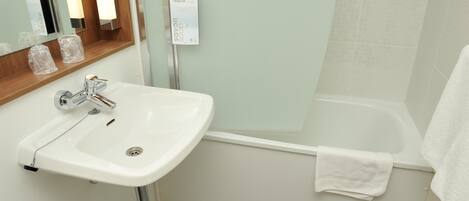 A bathroom with a white sink, a mirror, a shower, and a towel hanging on the wall.