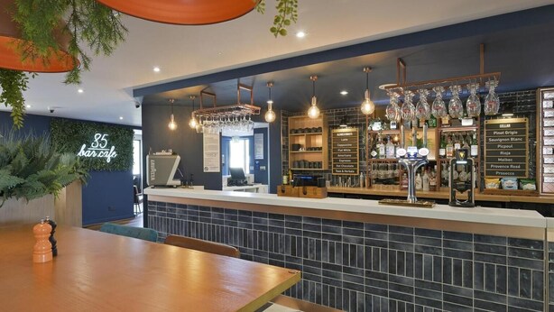 Una zona de bar con mostrador, asientos y un panel de menú.