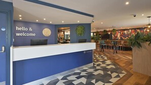 Una recepción con un letrero que dice 'bienvenidos' y un reloj, y el logotipo de Travelodge.