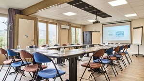 A conference room with a long table, chairs, a projector screen, and a whiteboard.