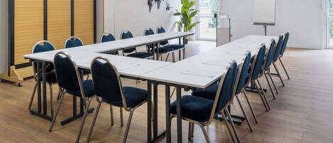 A conference room with a long table, blue chairs, a world map on the wall, and a whiteboard.